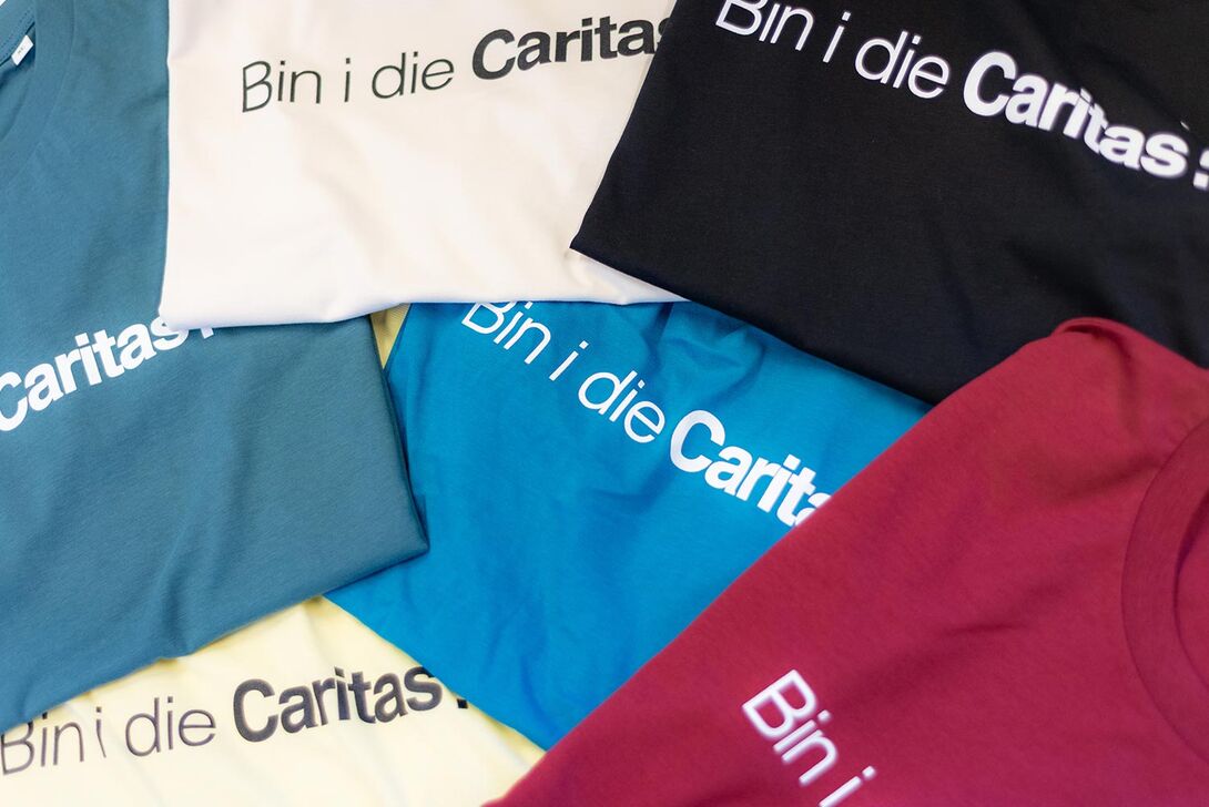 Sechs unterschiedlich gefärbte youngCaritas-T-Shirts gefalten