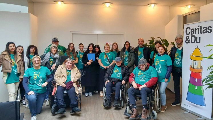 Eine Gruppe von Freiwilligen in grünen T-Shirts posiert in einem Raum für ein Gruppenfoto, während sie sich engagieren.
