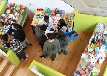 Eine Gruppe von Jugendlichen sammelt verschiedene Lebensmittel und Hygieneartikel in einem Einkaufsbereich.