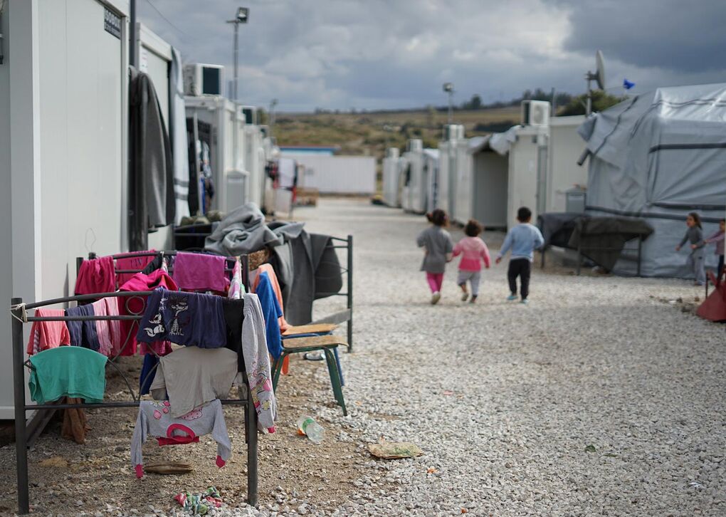 Blick auf eine Flüchtlingsunterkunft mit Kindern, die spielen, während Wäsche zum Trocknen aufgehängt ist.