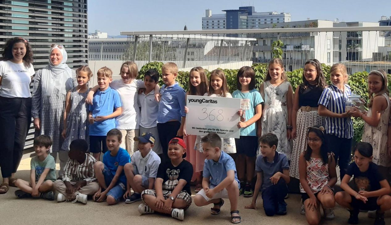 Eine Gruppe von Kindern von youngCaritas posiert mit einem Schild, das eine Spendenhöhe von 368 anzeigt; eine Feier des Engagements.