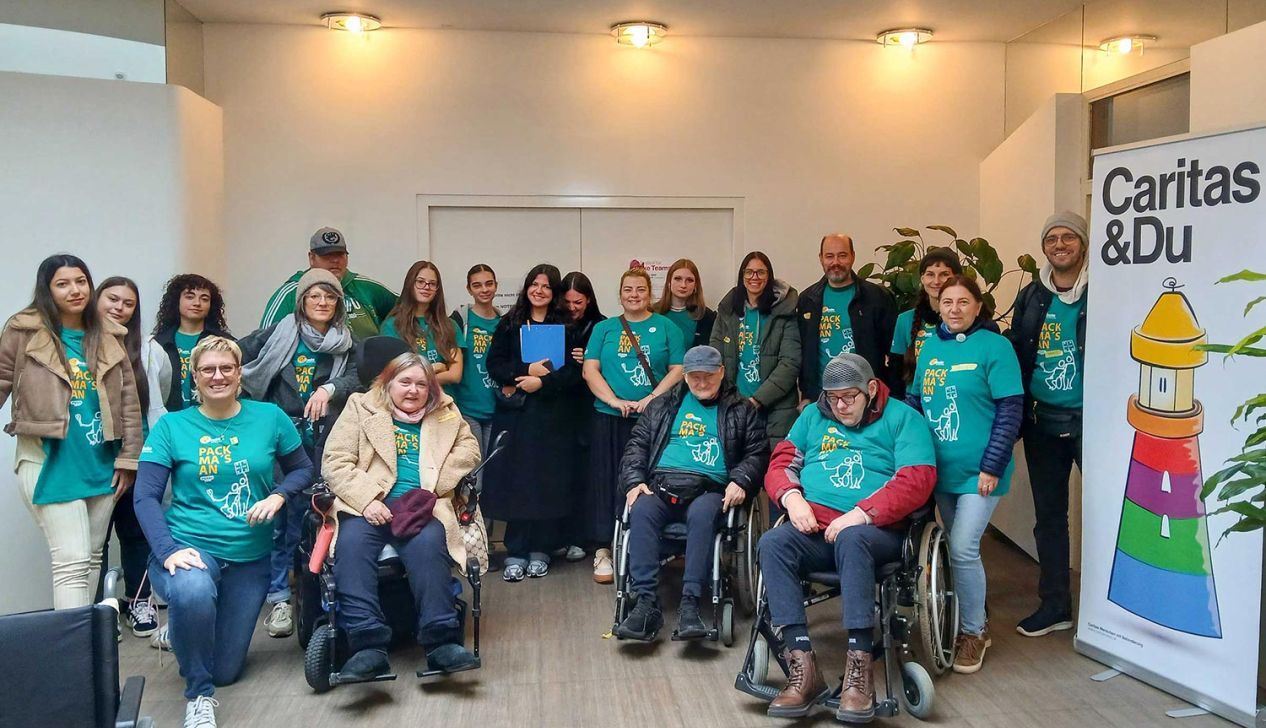 Eine Gruppe von Freiwilligen in grünen T-Shirts posiert in einem Raum für ein Gruppenfoto, während sie sich engagieren.