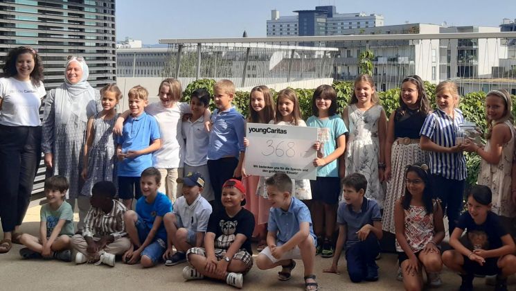 Eine Gruppe von Kindern von youngCaritas posiert mit einem Schild, das eine Spendenhöhe von 368 anzeigt; eine Feier des Engagements.