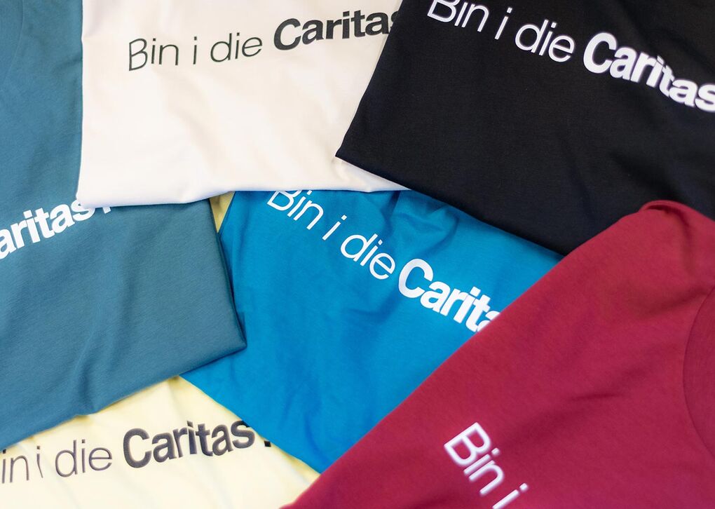 Sechs unterschiedlich gefärbte youngCaritas-T-Shirts gefalten
