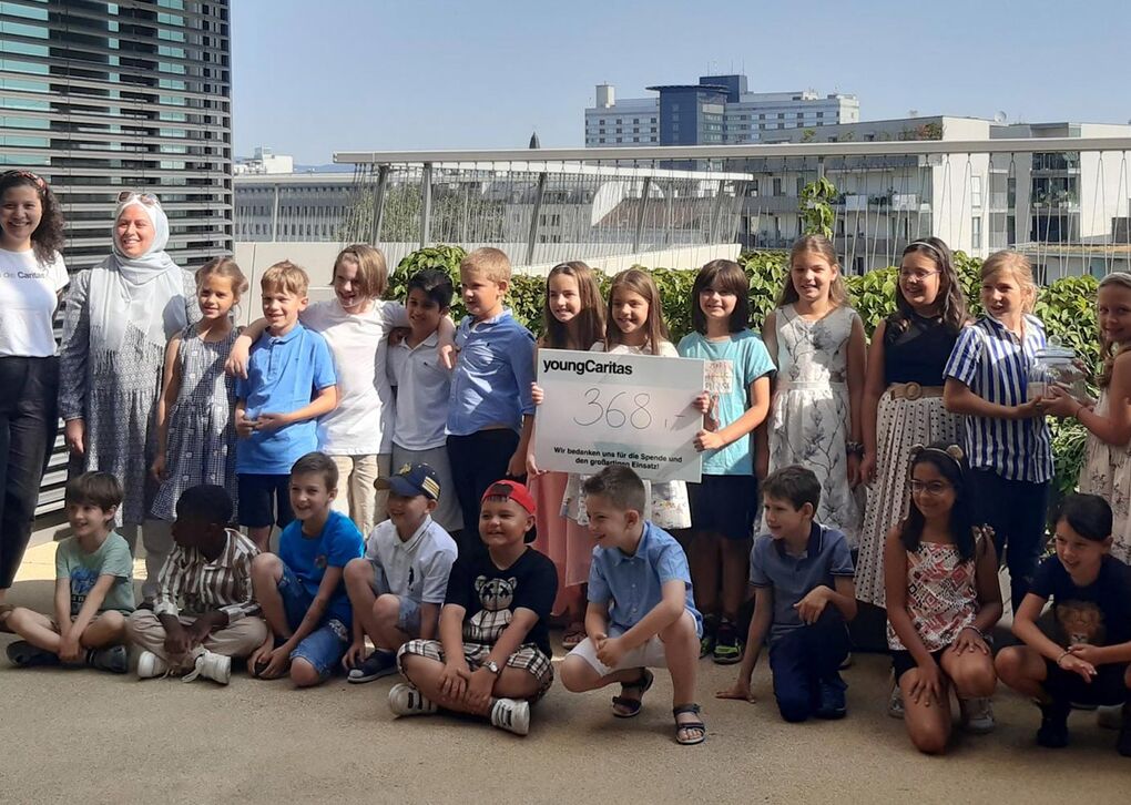 Eine Gruppe von Kindern von youngCaritas posiert mit einem Schild, das eine Spendenhöhe von 368 anzeigt; eine Feier des Engagements.