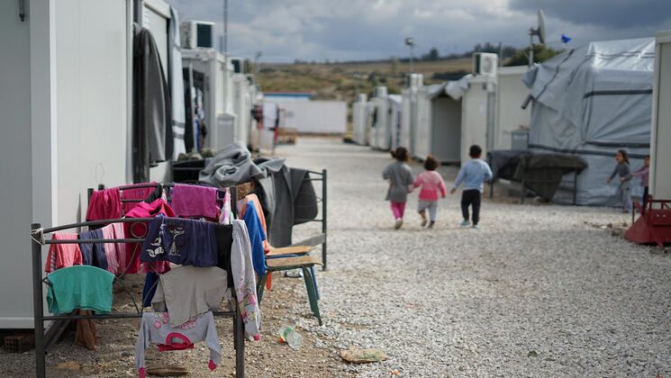 Blick auf eine Flüchtlingsunterkunft mit Kindern, die spielen, während Wäsche zum Trocknen aufgehängt ist.