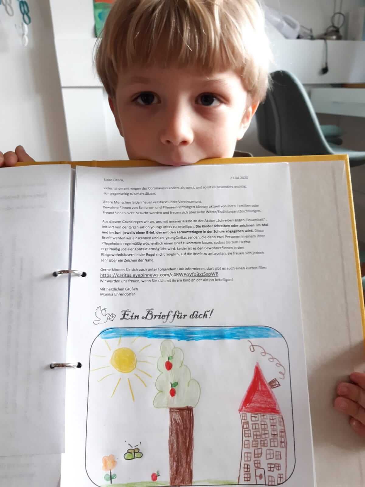 Ein Kind hält einen Brief mit Zeichnung für die youngCaritas Briefaktion.