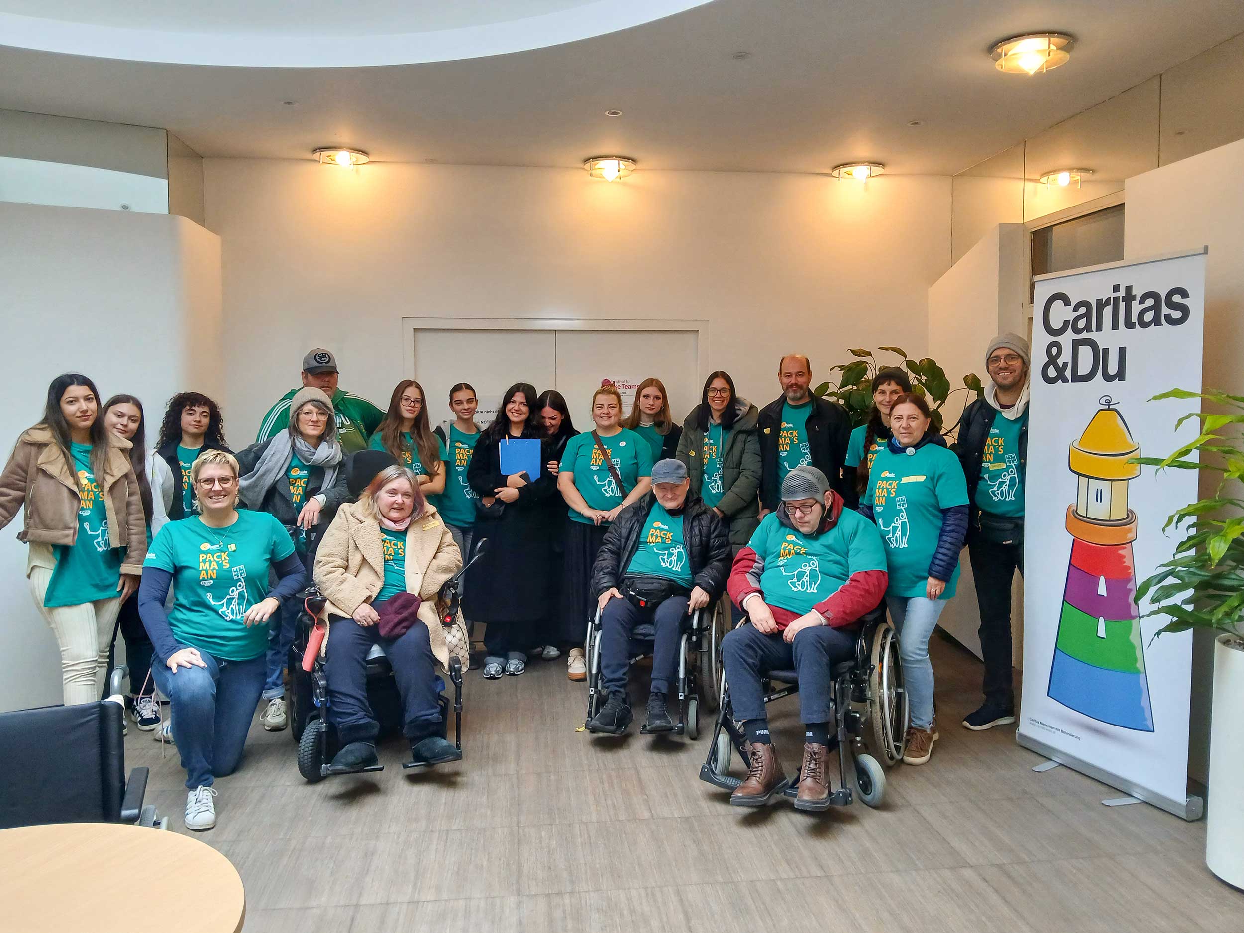 Gruppe von Schüler*innen, Caritas Mitarbeiter*innen und anderen Menschen lächeln in die Kamera, sie tragen Tshirts mit der Aufschrift 
